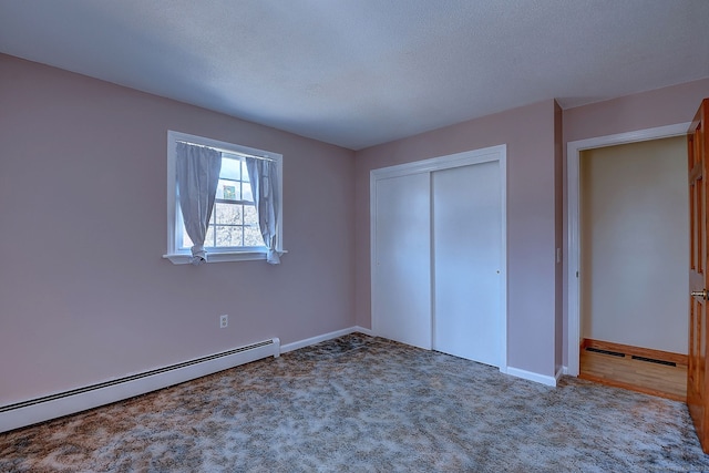 unfurnished bedroom with a baseboard heating unit, a textured ceiling, a closet, carpet, and baseboards