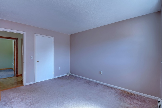 unfurnished bedroom featuring a baseboard radiator, baseboards, and carpet flooring