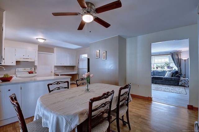 dining room featuring light wood finished floors, baseboards, and a ceiling fan