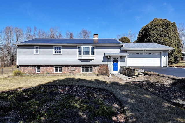 tri-level home with a garage, driveway, and a chimney