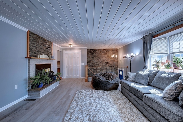 living area featuring wood finished floors, baseboards, wood ceiling, crown molding, and a large fireplace