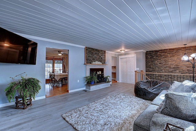 living room featuring a large fireplace, baseboards, crown molding, wood finished floors, and a ceiling fan