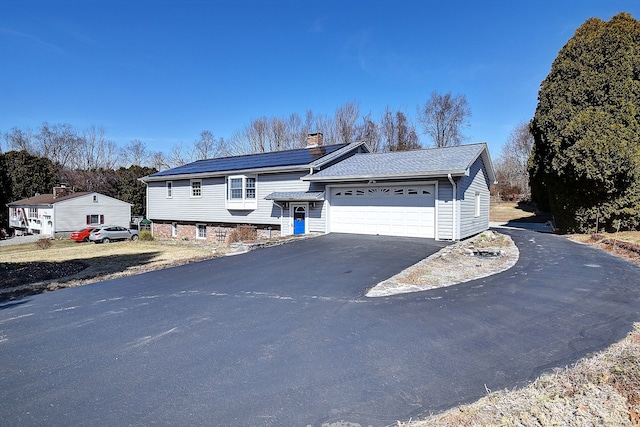 view of front of house featuring driveway, an attached garage, and a chimney