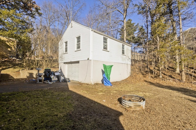 view of home's exterior featuring an attached garage, a fire pit, and driveway