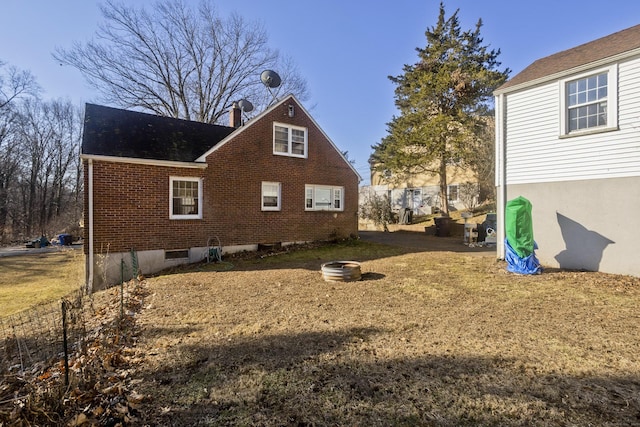 view of home's exterior with a yard, brick siding, and an outdoor fire pit