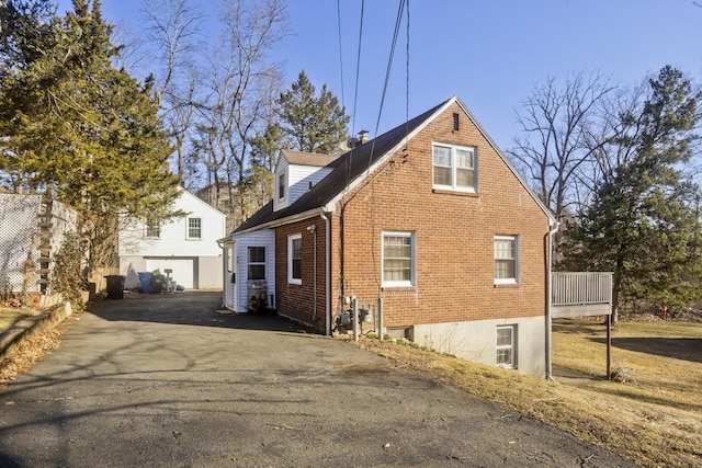 view of home's exterior featuring aphalt driveway, a garage, and brick siding