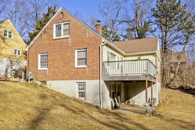 back of property featuring a wooden deck, a chimney, a yard, and roof with shingles