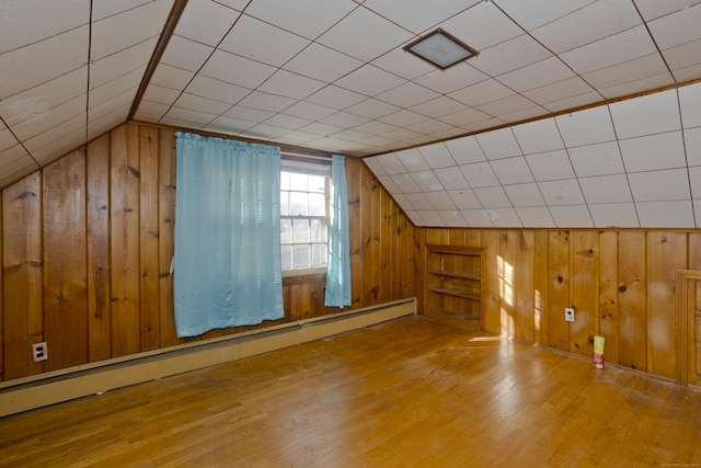 bonus room with a baseboard heating unit, lofted ceiling, wood finished floors, and wood walls