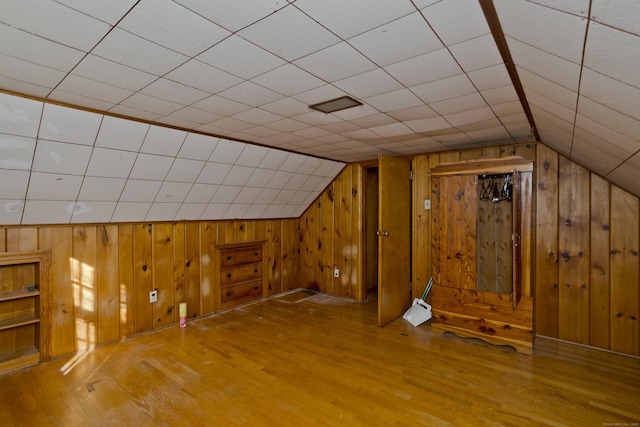 bonus room with lofted ceiling, wooden walls, and wood finished floors