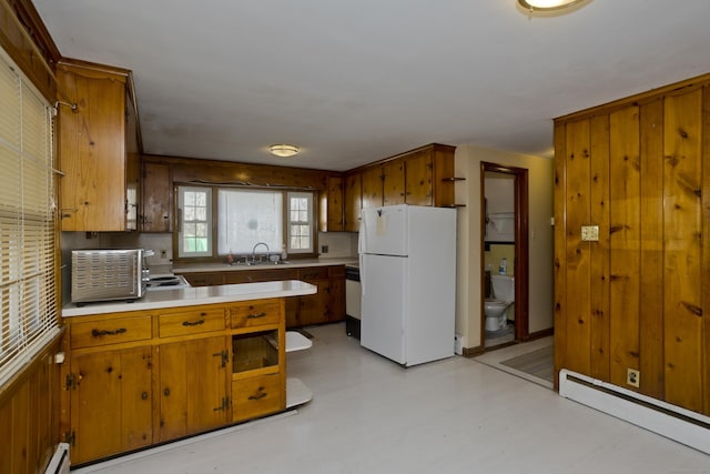 kitchen with a sink, white appliances, brown cabinetry, and a baseboard radiator