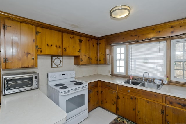 kitchen featuring a toaster, light countertops, brown cabinets, white electric range oven, and a sink