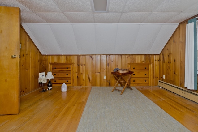 bonus room featuring vaulted ceiling, wood walls, and wood finished floors