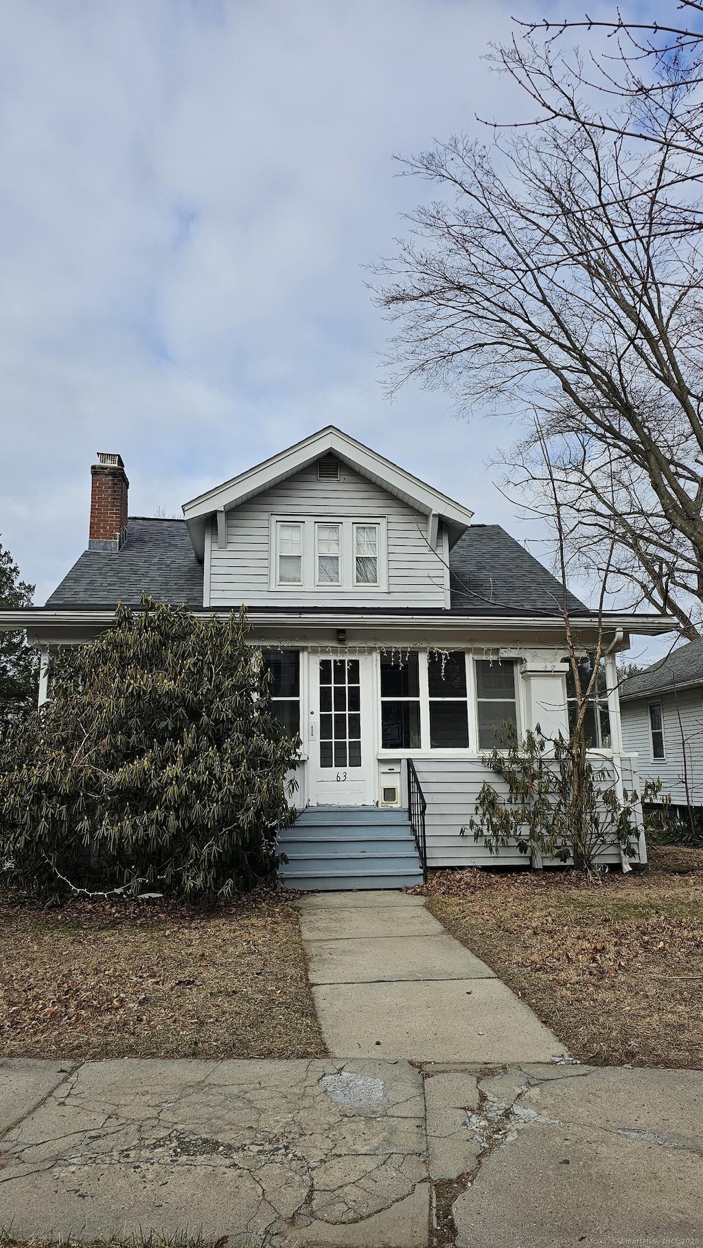 view of front facade with a chimney and roof with shingles