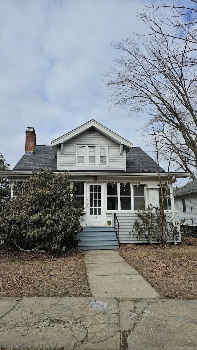 view of front facade with a chimney and roof with shingles