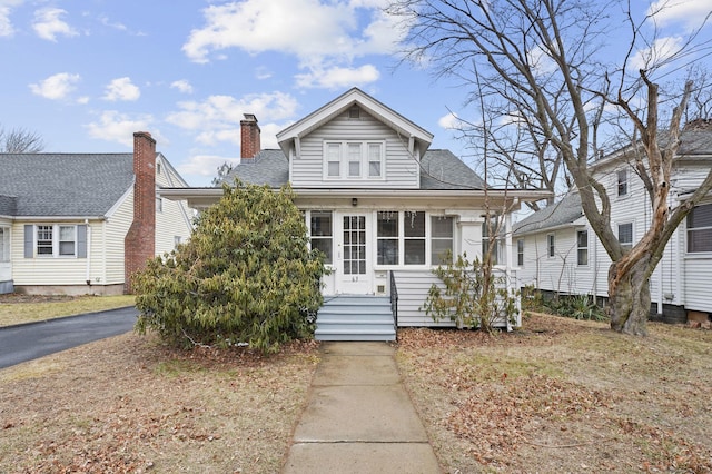 bungalow-style home with roof with shingles and a chimney