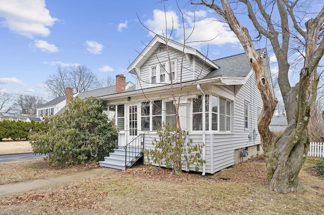 bungalow-style house with fence, roof with shingles, and a chimney
