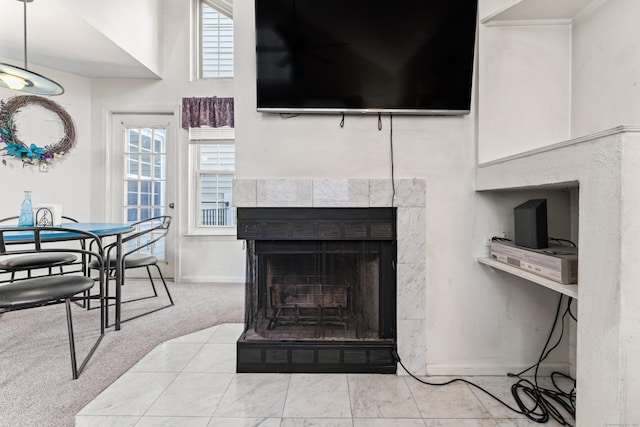 living room with a tile fireplace, baseboards, a high ceiling, and carpet