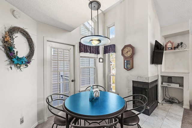 dining space featuring baseboards, a tile fireplace, a towering ceiling, and a textured ceiling