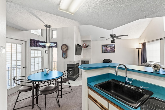 kitchen with a sink, plenty of natural light, ceiling fan, and a tile fireplace