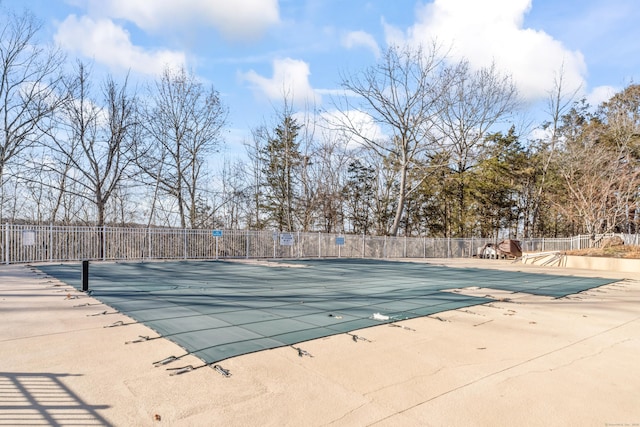 community pool with a patio area and fence