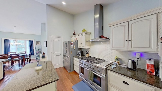 105 Mashentuck Rd, Killingly, CT 06239 - kitchen with stainless steel appliances, wall chimney range hood, dark stone countertops, a chandelier, and tasteful backsplash