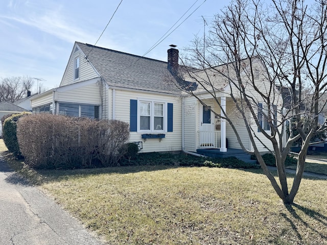 view of front of property featuring a front lawn, a chimney, and a shingled roof