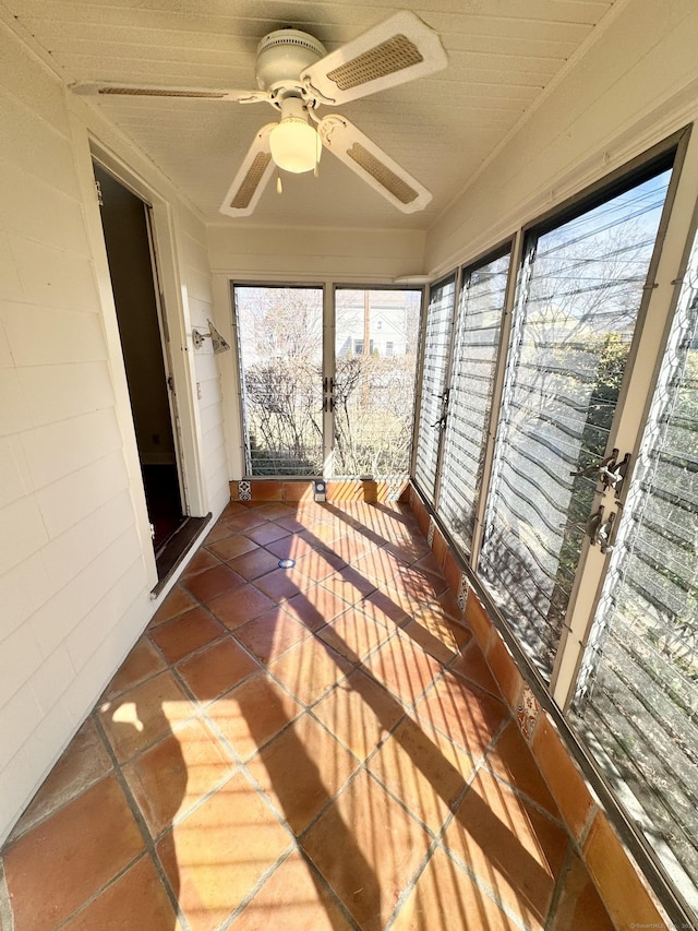 unfurnished sunroom with ceiling fan