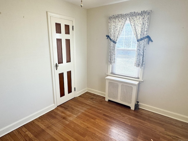 unfurnished room featuring radiator, baseboards, and wood finished floors