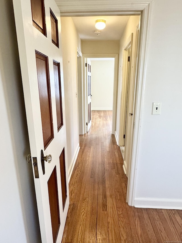 hallway with baseboards and wood-type flooring