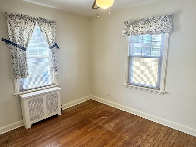 empty room with dark wood-type flooring, radiator, baseboards, and ceiling fan