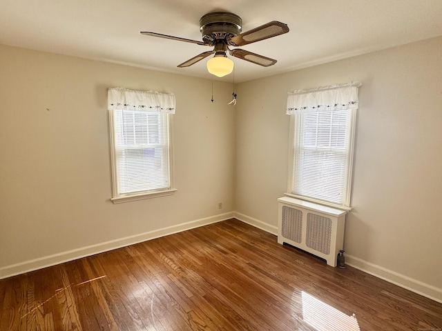 spare room with baseboards, plenty of natural light, radiator, and hardwood / wood-style flooring