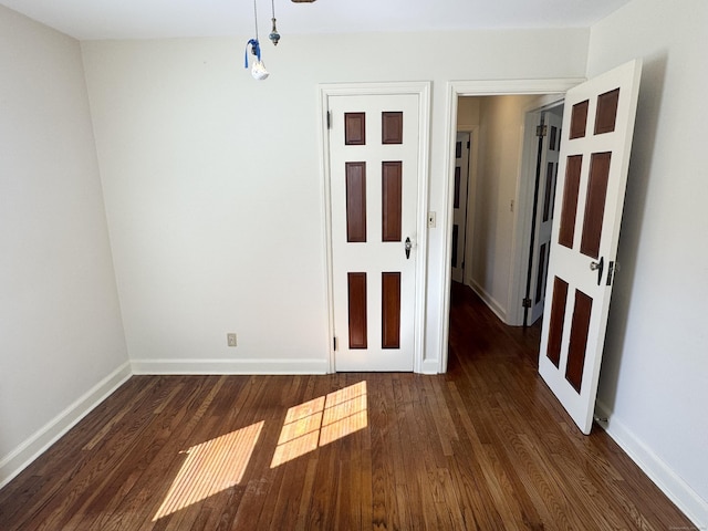 empty room featuring dark wood-type flooring and baseboards