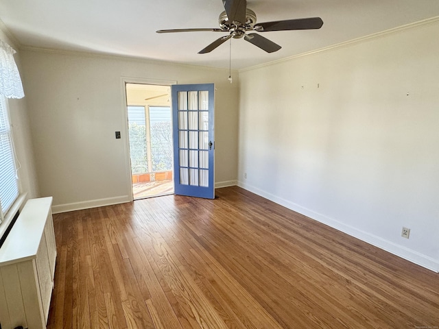 spare room with baseboards, wood-type flooring, ceiling fan, and crown molding