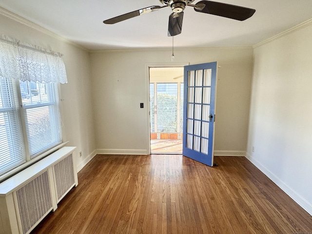 empty room featuring ornamental molding, radiator, wood finished floors, and ceiling fan