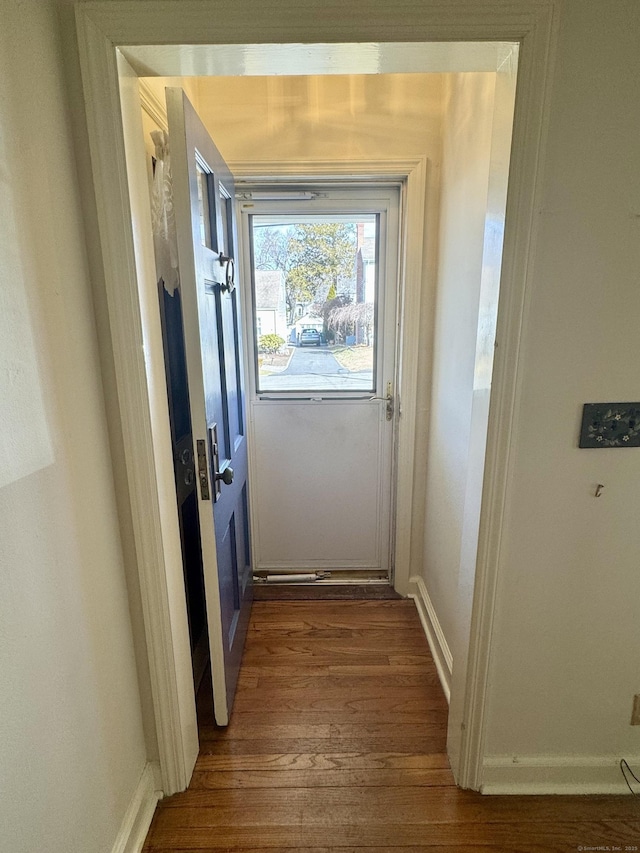 doorway featuring baseboards and wood finished floors