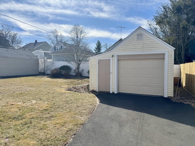 detached garage with aphalt driveway and fence