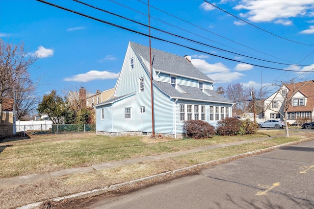view of side of home with fence, a lawn, and a shingled roof