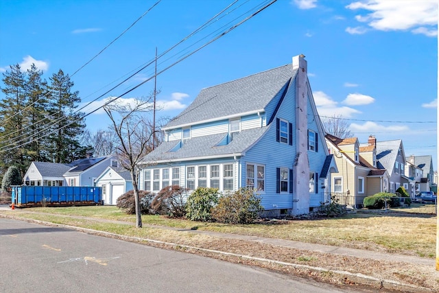 view of front facade with a residential view, a front yard, roof with shingles, and a chimney