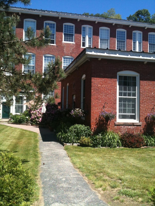 exterior space featuring brick siding and a lawn