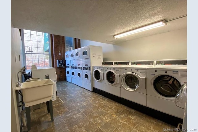 common laundry area featuring a sink, a textured ceiling, independent washer and dryer, and stacked washer / dryer