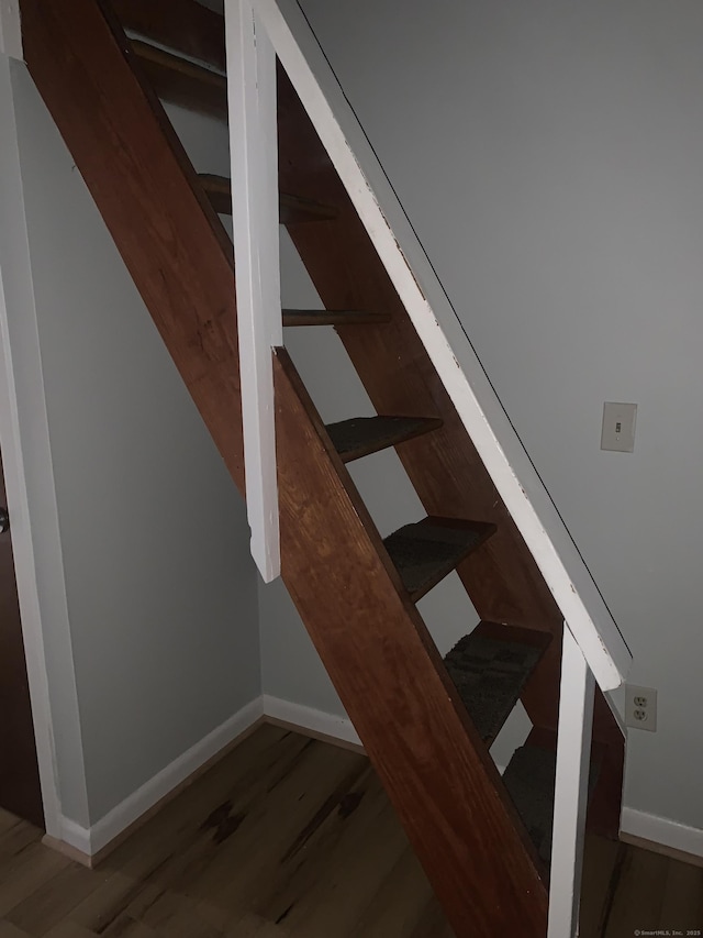 staircase with wood finished floors and baseboards