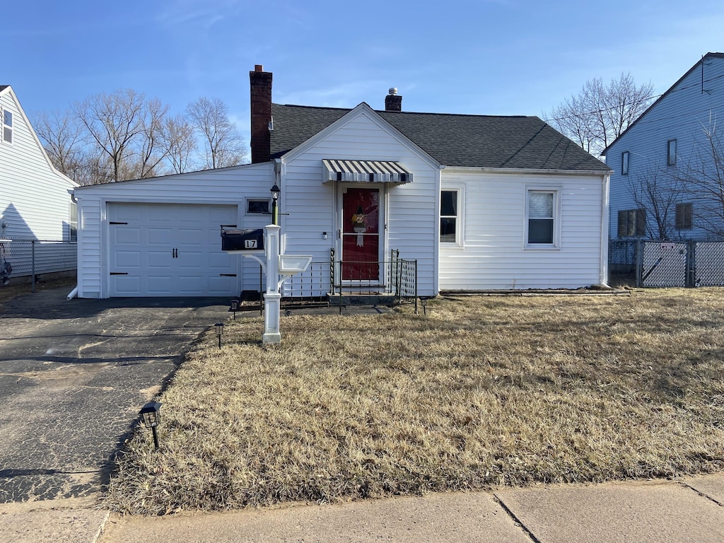 view of front of house with fence, aphalt driveway, a front yard, a chimney, and an attached garage