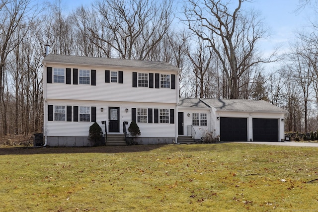 colonial inspired home featuring entry steps, a front lawn, an attached garage, and driveway