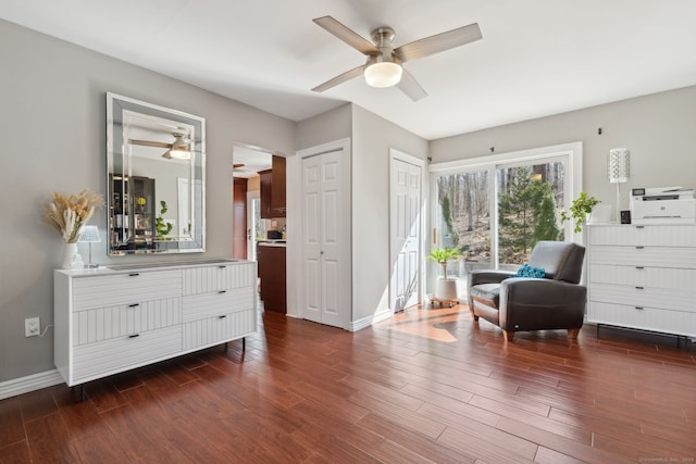 sitting room featuring baseboards, dark wood-type flooring, and a ceiling fan