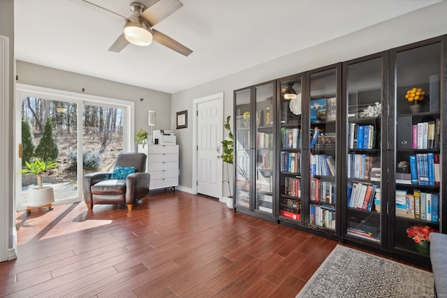 sitting room with baseboards, wood finished floors, and a ceiling fan