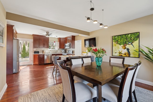 dining room with beamed ceiling, ceiling fan, dark wood-type flooring, and baseboards