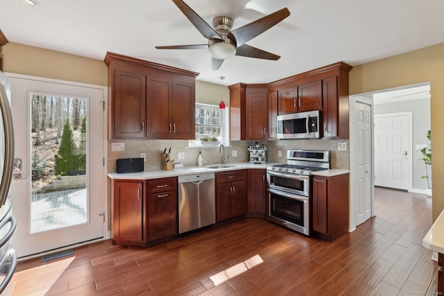 kitchen with a ceiling fan, a sink, stainless steel appliances, light countertops, and tasteful backsplash