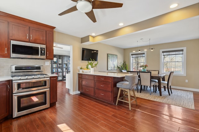 kitchen featuring ceiling fan, light countertops, a peninsula, and stainless steel appliances