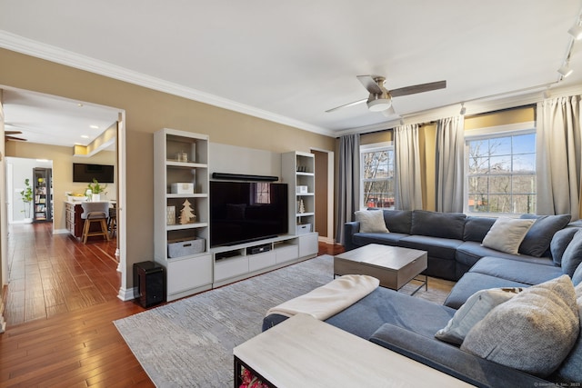 living area with baseboards, ceiling fan, ornamental molding, and hardwood / wood-style flooring