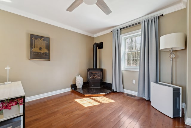 living area featuring baseboards, crown molding, ceiling fan, and wood-type flooring